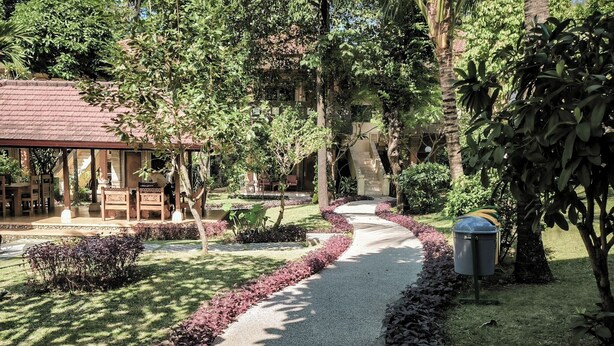 A pathway leading to a building with a covered seating area and a small water feature. -  Melasti Kuta Beach Hotel and Spa (Kuta)