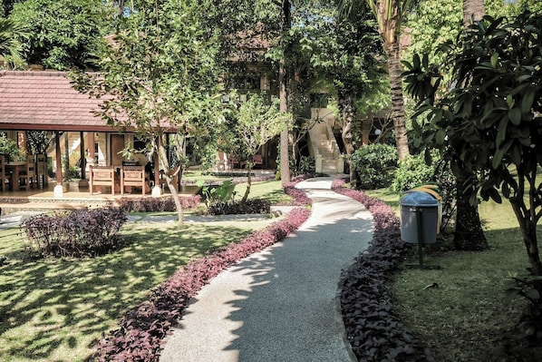 A pathway leading to a building with a covered seating area and a small water feature. -  Melasti Kuta Beach Hotel and Spa (Kuta)