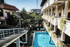 A swimming pool with a checkered pattern, surrounded by buildings with balconies and vegetation. -  Melasti Kuta Beach Hotel and Spa (Kuta)