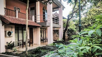 A multi-story building with a balcony, outdoor seating, and a garden area.