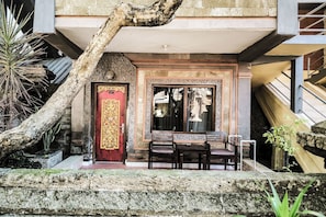 A traditional building with a red door, a staircase, and a small outdoor seating area with two chairs. - Melasti Kuta Beach Hotel and Spa (Kuta)
