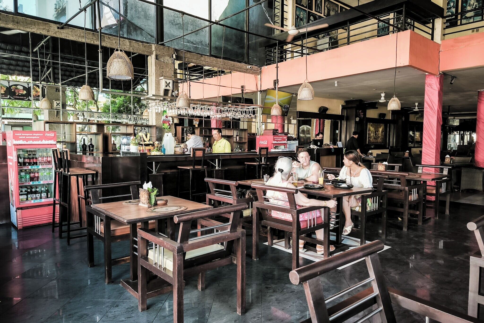 Um restaurante com mesas e cadeiras de madeira, um espaço de bar e uma máquina de venda automática.