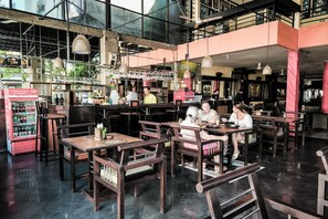 A restaurant with wooden tables and chairs, a bar area, and a vending machine. - Melasti Kuta Beach Hotel and Spa (Kuta)