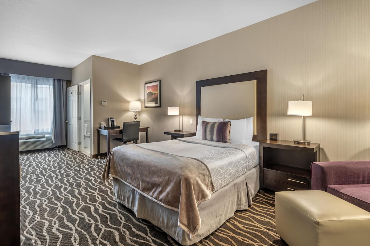 A hotel room with a large bed, two bedside tables, a desk, and a chair.