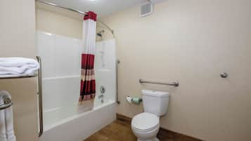 Un baño con bañera, inodoro y barras de apoyo.