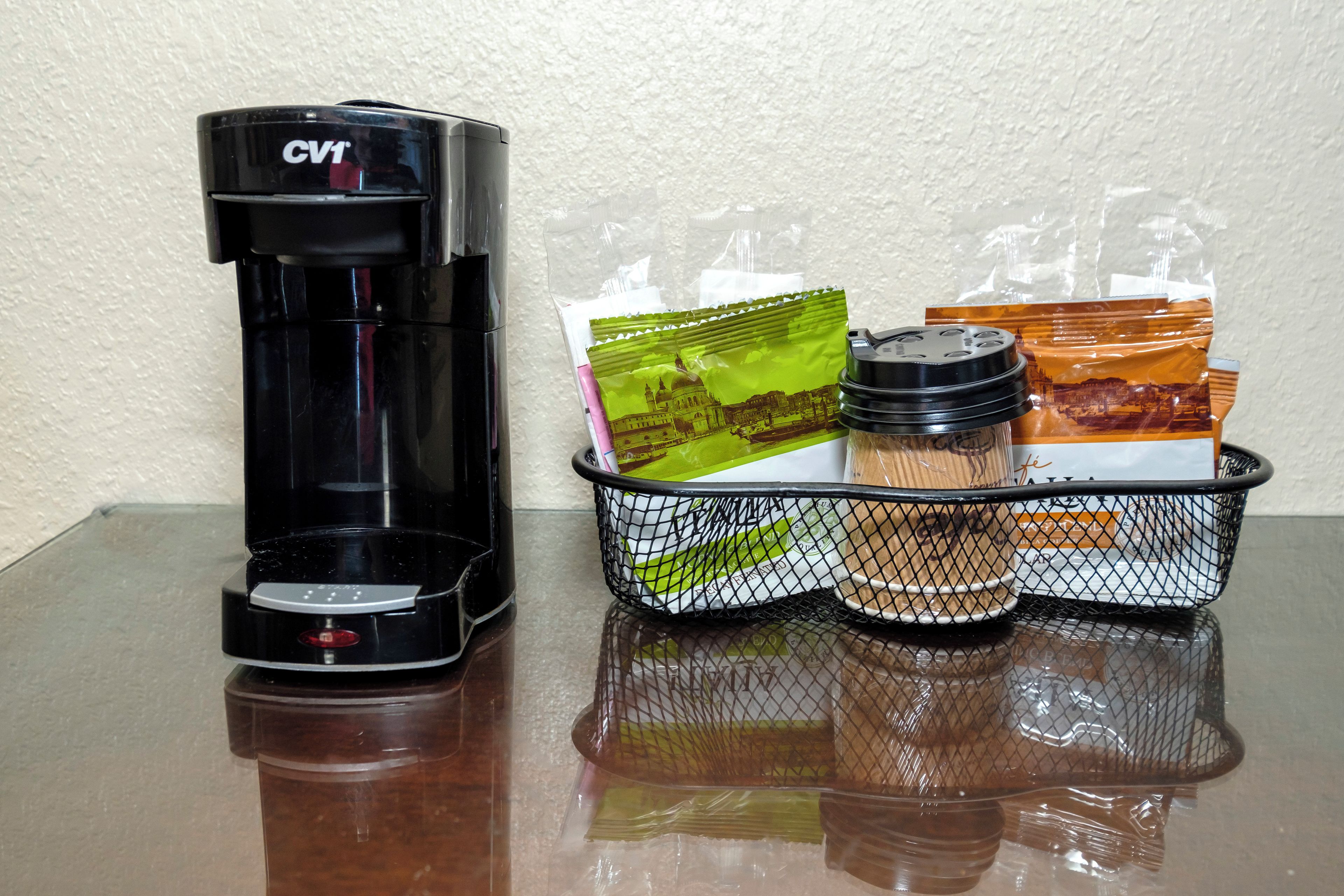 A coffee maker and a basket with coffee pods and a coffee bag on a table.