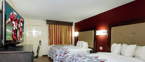 Une chambre d’hôtel équipée d’une télévision, d’un lit, d’un bureau et d’une fenêtre avec des rideaux.