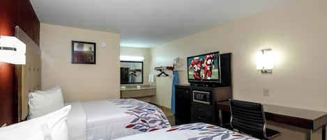 A hotel room with two beds, a television, a desk, and a mirror.
