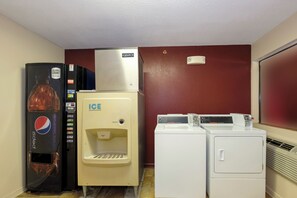 Un cuarto de servicio compacto con refrigerador, dispensador de agua y un conjunto de lavadoras y secadoras.