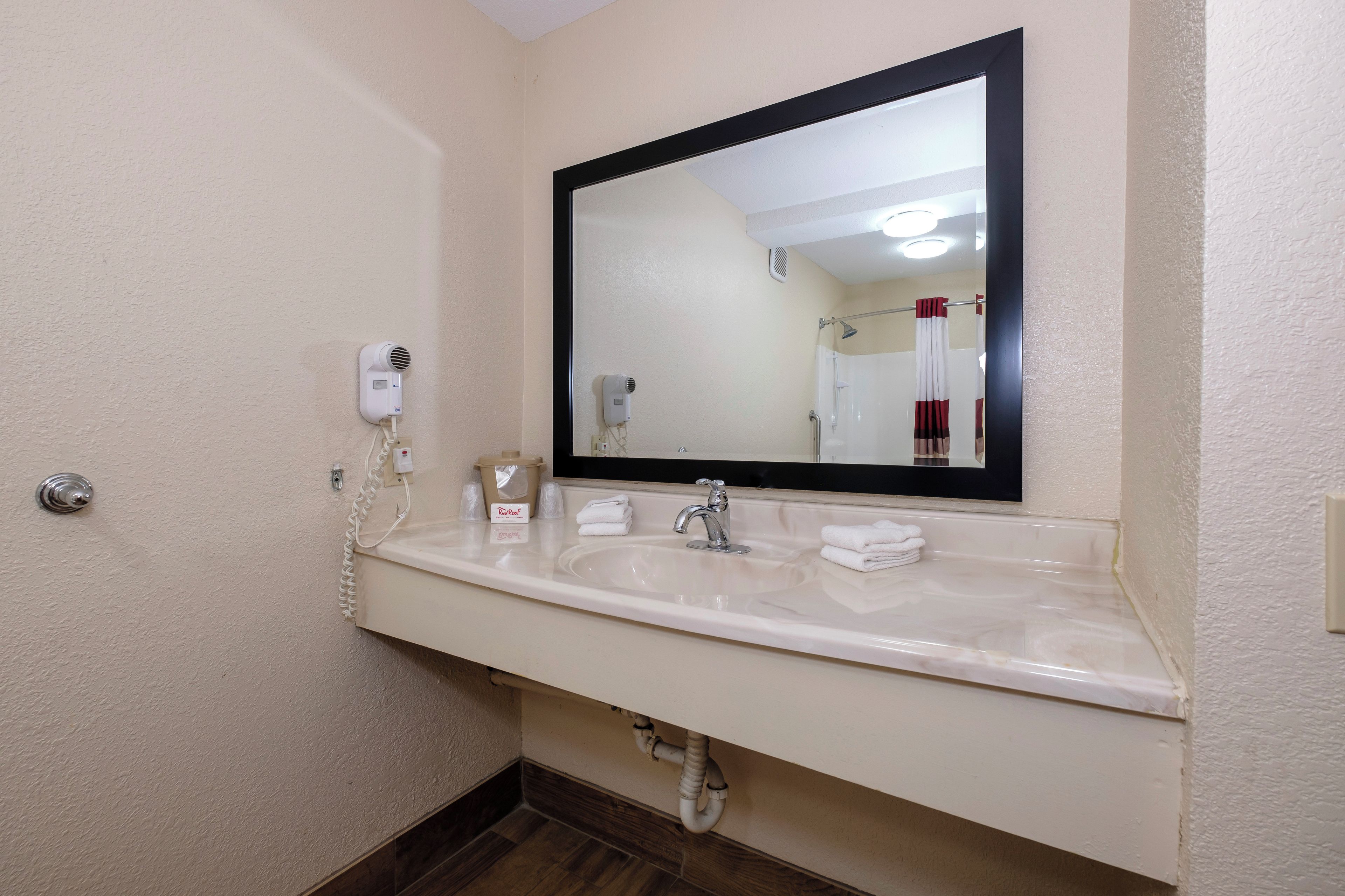 A bathroom with a white sink, a mirror, a hairdryer, and a towel rack.