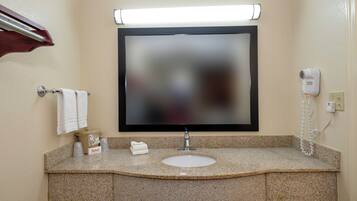 A bathroom with a granite countertop, a sink, a mirror, a towel rack, and a hairdryer.