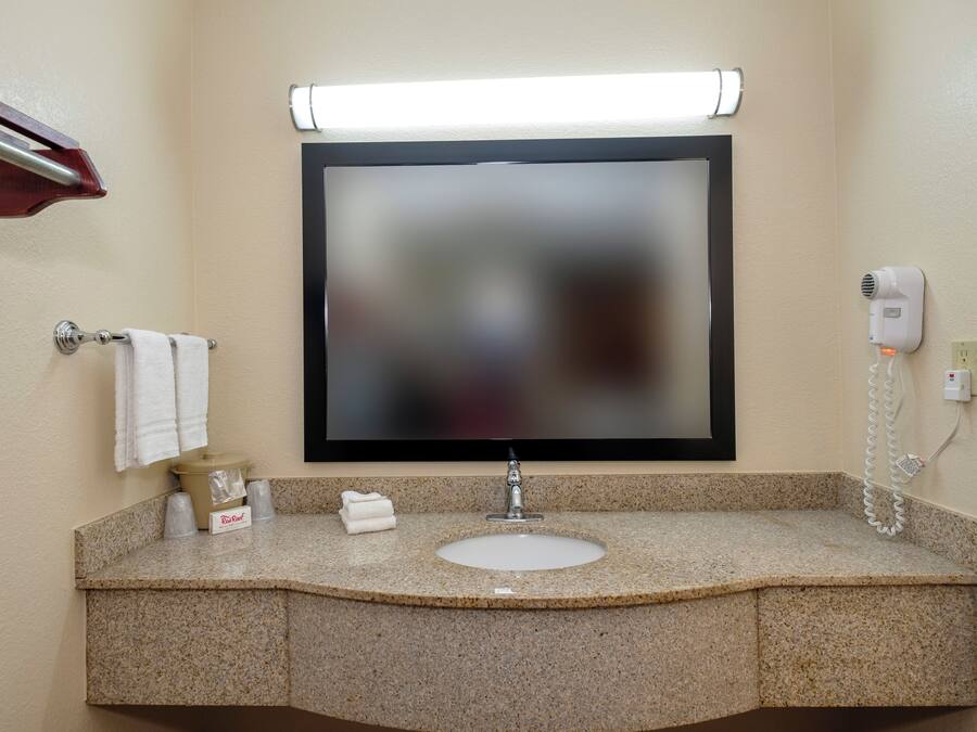 A bathroom with a granite countertop, a sink, a mirror, a towel rack, and a hairdryer.