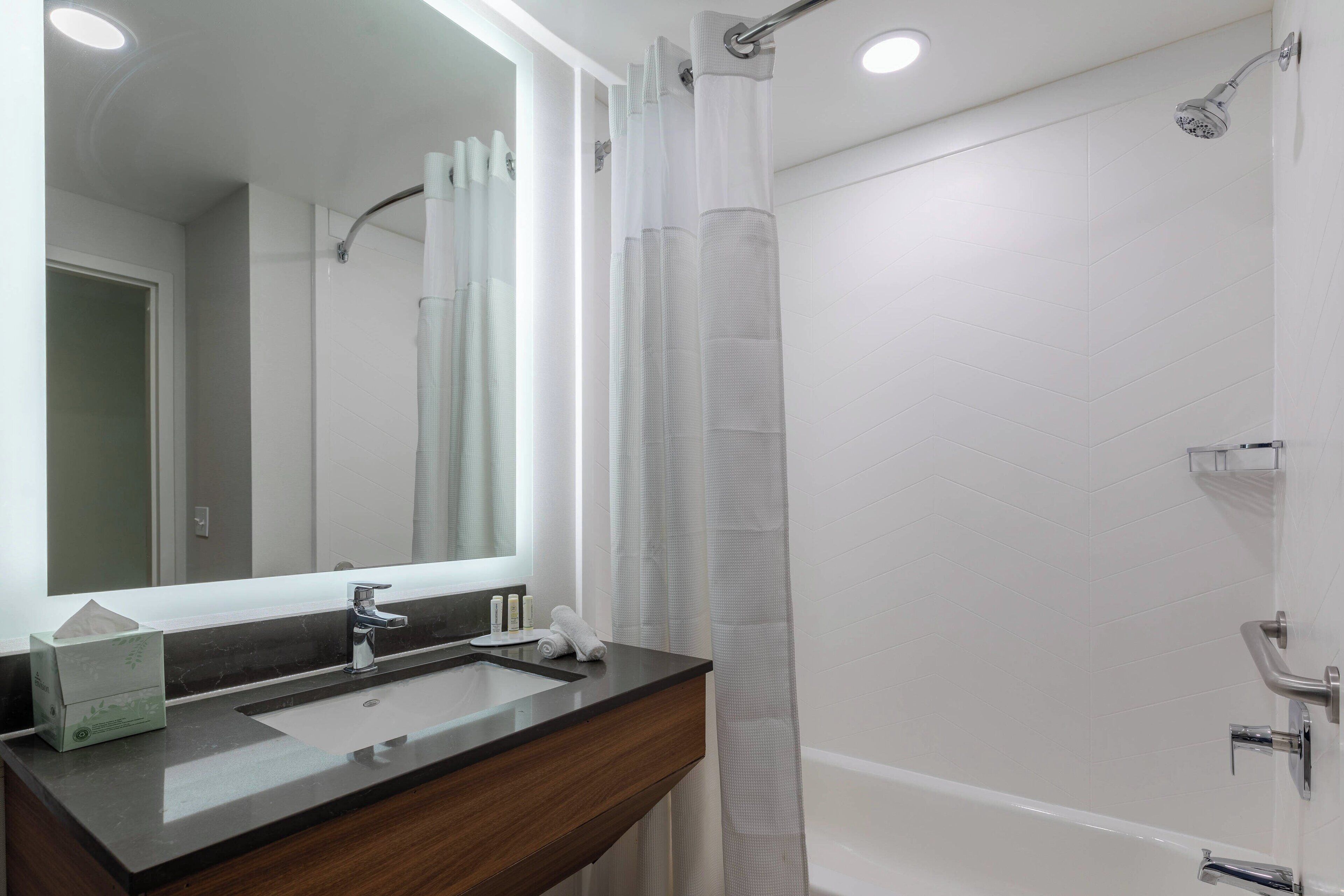 Un baño moderno con lavamanos doble, un espejo grande, ducha con puerta de vidrio y bañera.