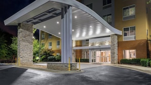 L’entrée d’un hôtel, avec un passage couvert, des piliers en pierre et une façade bien éclairée.