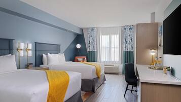 A hotel room with two beds, a desk, a chair, a lamp, and a large mirror.