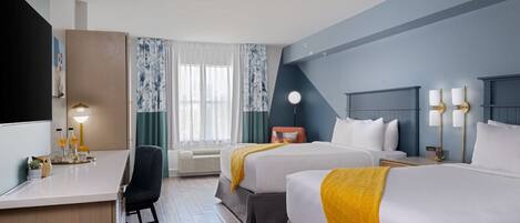Habitación de hotel con dos camas, un escritorio, una silla, un televisor y una ventana con cortinas.