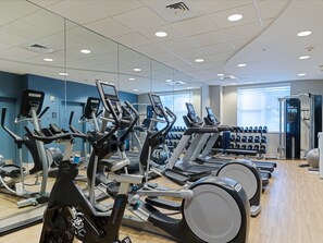 A gym with multiple treadmills, elliptical machines, and free weights. - voco Sarasota by IHG (Sarasota)