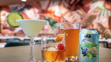A table with a martini glass, a short glass with a cherry, and a can of beer.