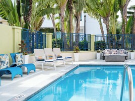 A poolside area with lounge chairs, a sofa, and a pool.