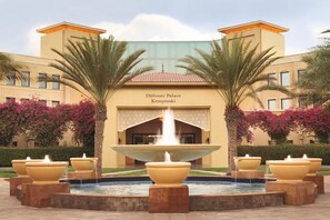 Palacio Djibouti Kempinski con una fuente central y palmeras.