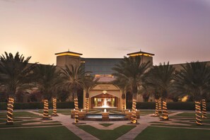 A hotel entrance with a fountain, palm trees, and a well-maintained garden. - Djibouti Palace Kempinski (Djibouti)