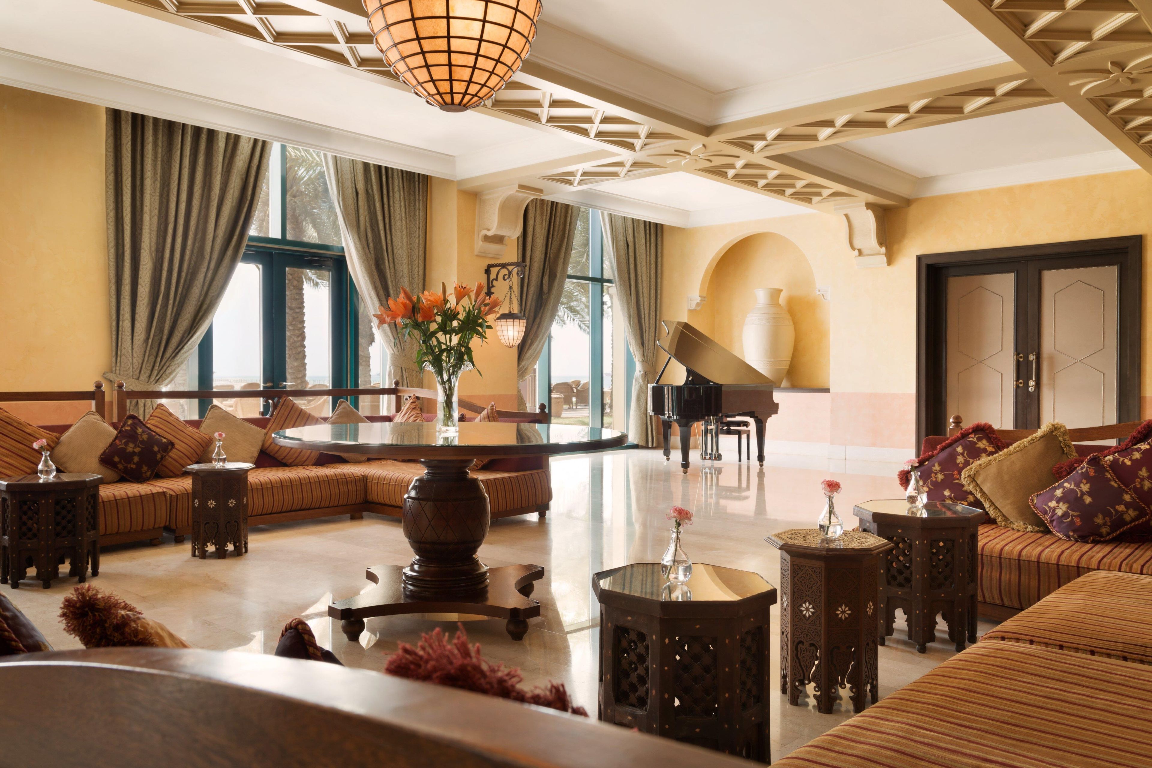 A spacious living room with a grand piano, comfortable seating, and a large window providing natural light.