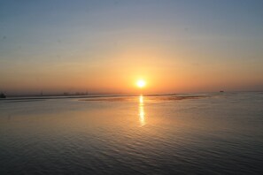Un atardecer sobre un cuerpo de agua tranquilo, con un barco a lo lejos.