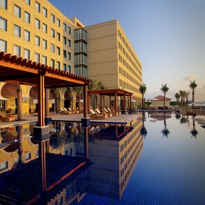 Ein Hotel mit Pool, Liegestühlen und Palmen.