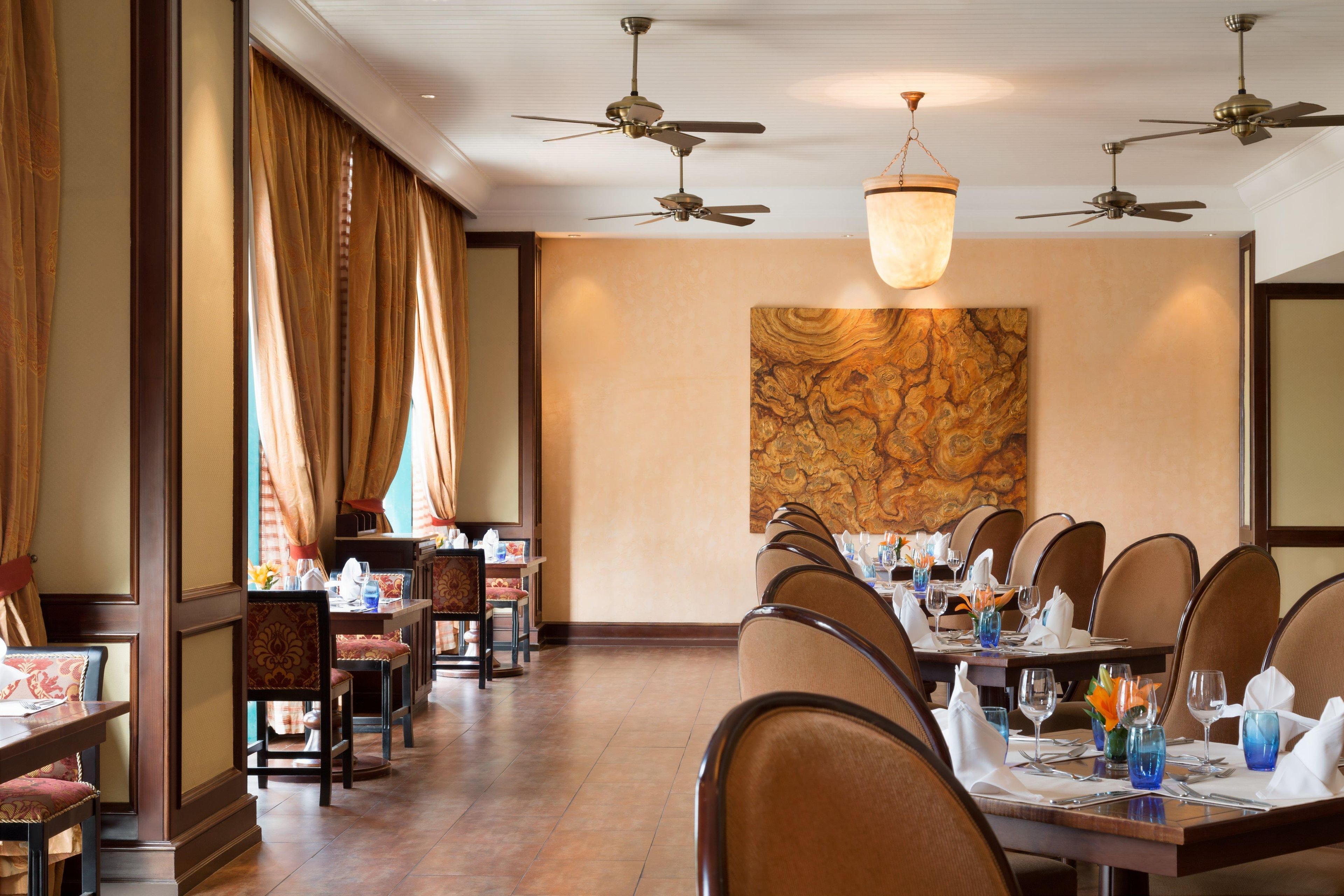 Un restaurante con varias mesas, sillas y ventiladores de techo.