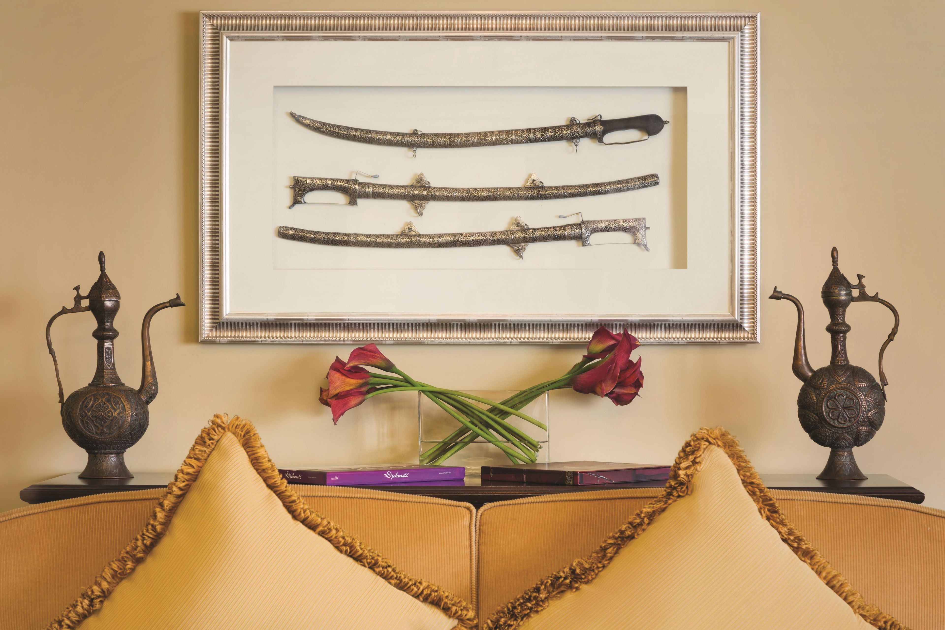 Ein gerahmtes Display mit verzierten Schwertern an einer Wand, eine Vase mit roten Blumen sowie zwei dekorative Vasen an jeder Seite.