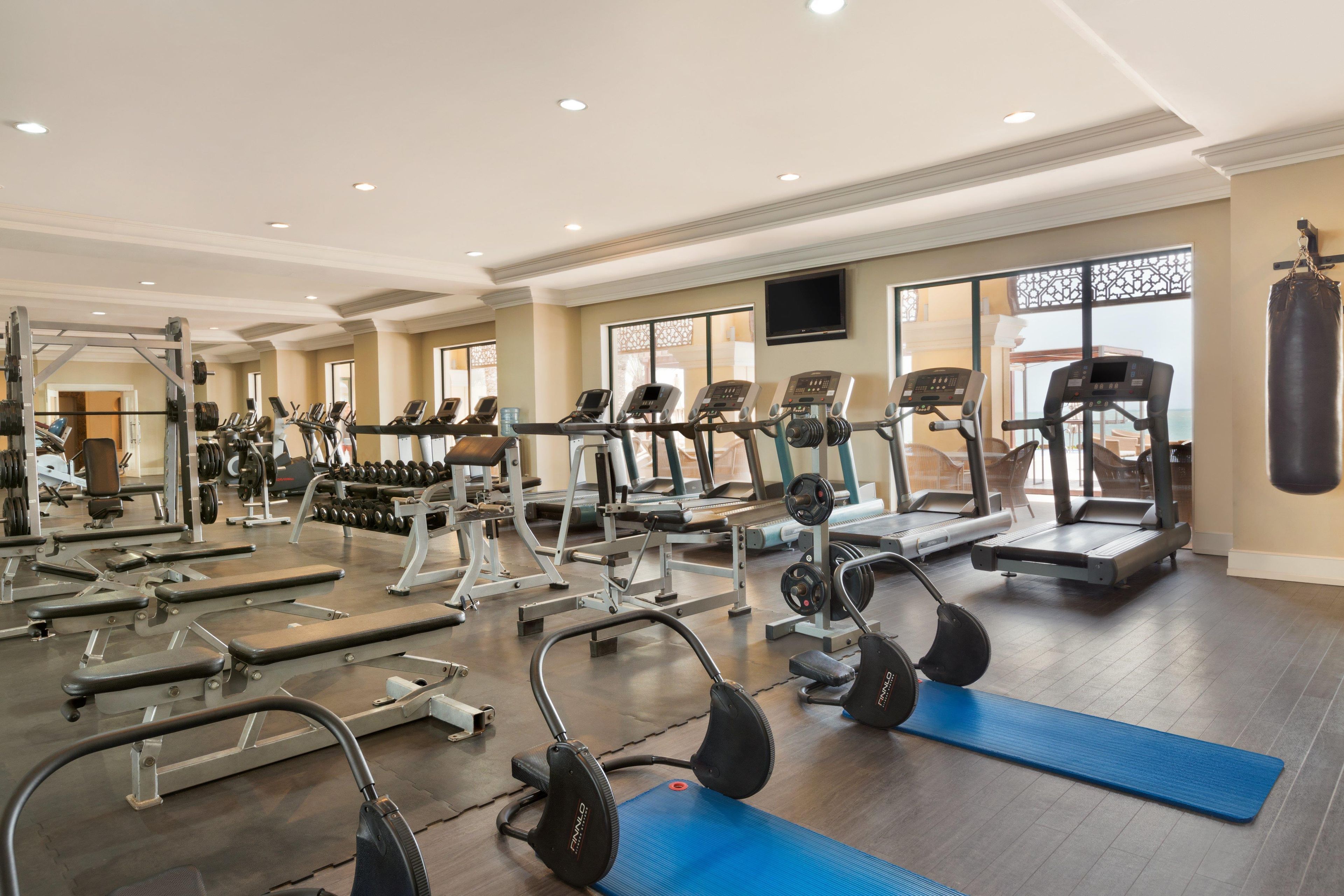 A gym with various exercise equipment, including treadmills, weight machines, and free weights.