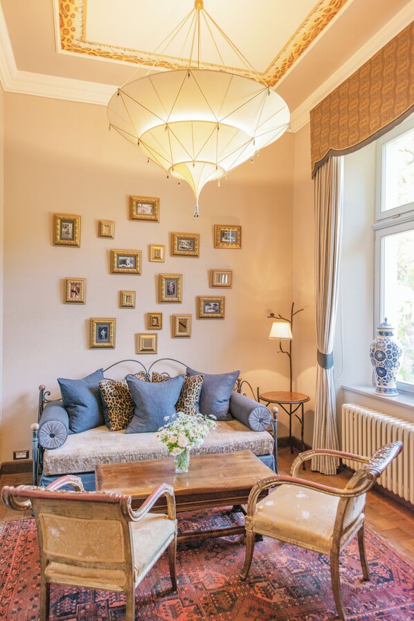 A cozy living room with a sofa, two armchairs, a coffee table, and a chandelier.