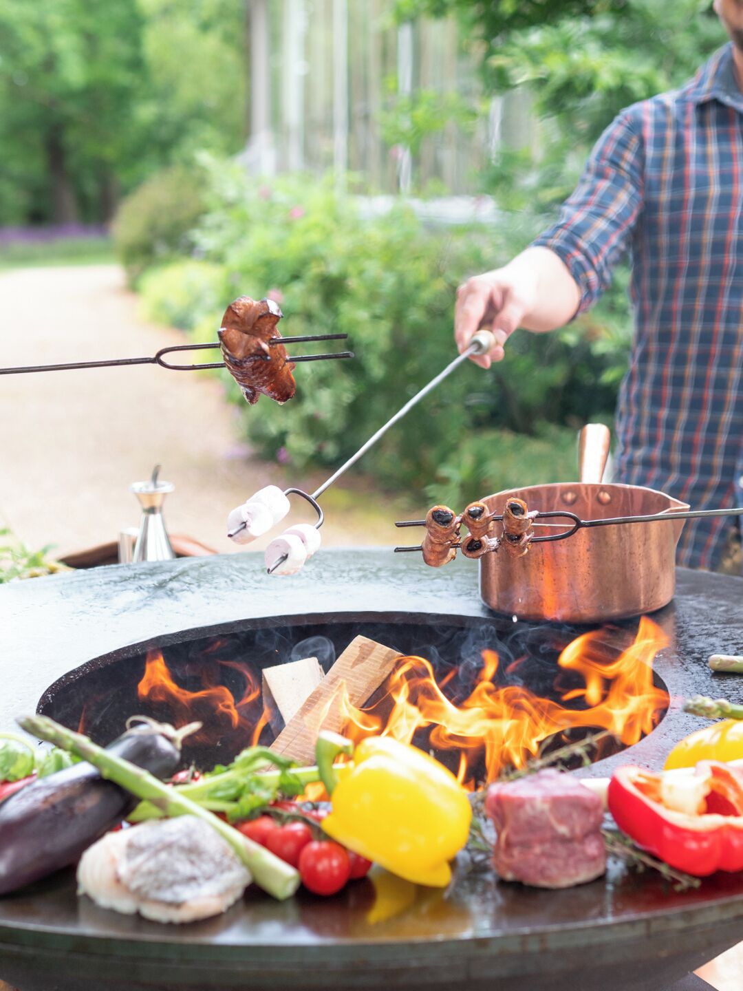 A person grilling various foods over an open fire.