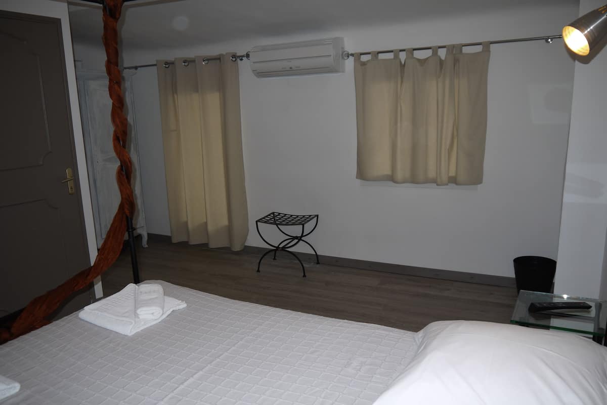 A bedroom with a bed, a small table, a chair, and a lamp.