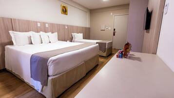 Quarto de hotel com uma cama grande, uma cama menor, uma mesa de cabeceira e um guarda-roupa.