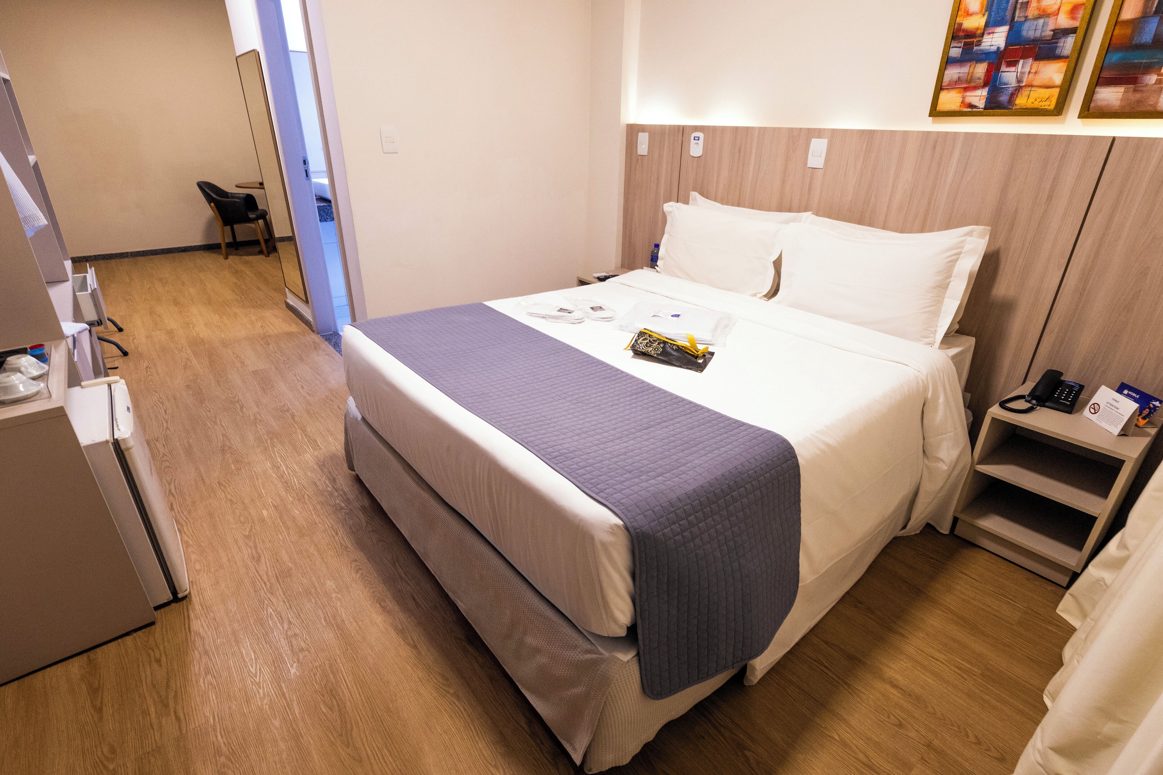 Een hotelkamer met een bed, nachtkastje en bureau met stoel.