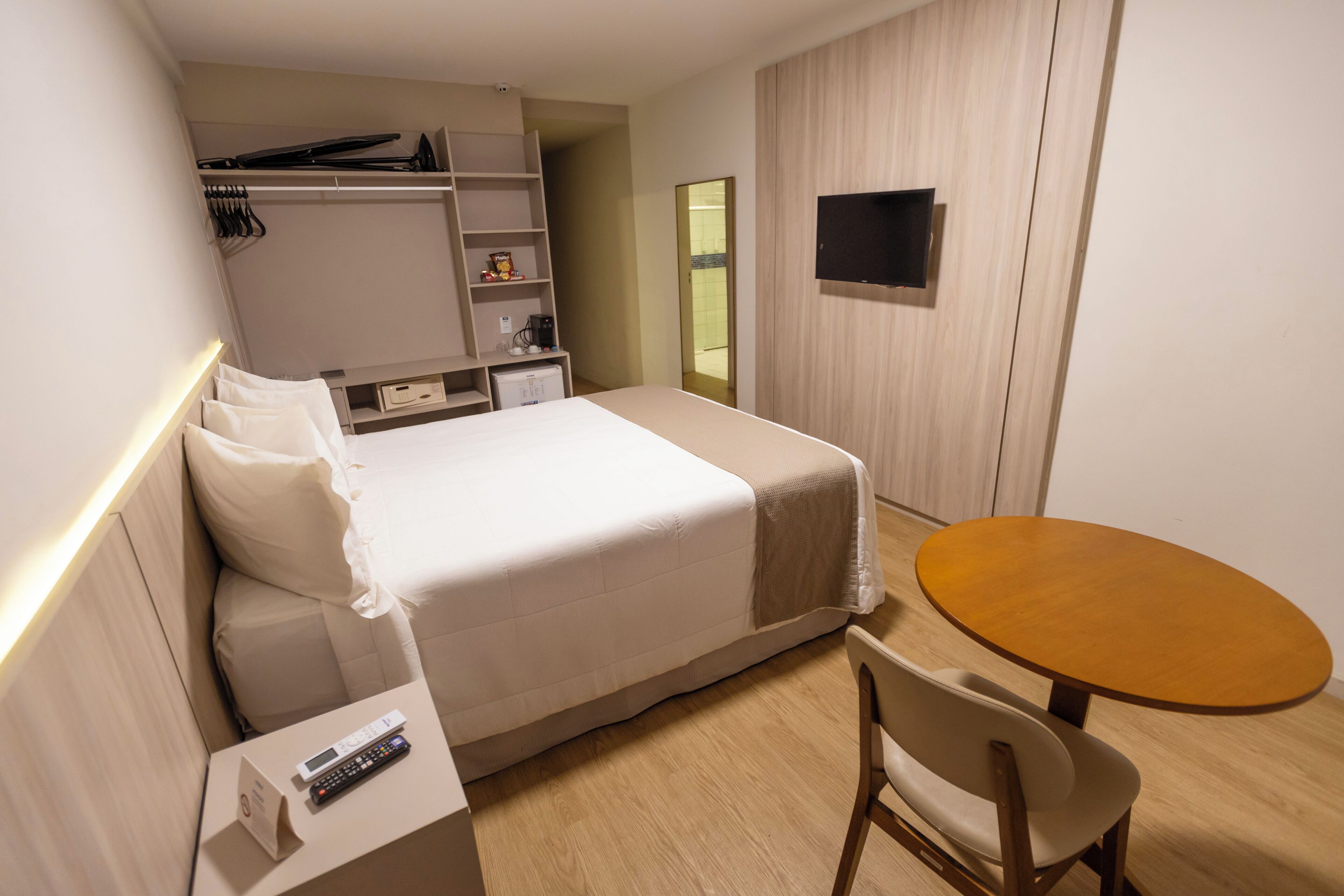 A hotel room with a bed, bedside table, chair, and a small round table.