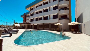 Una piscina al aire libre, sillones reclinables de piscina