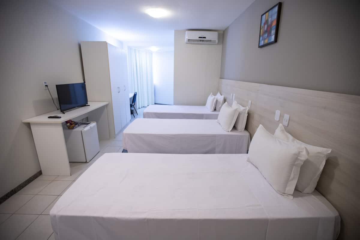 A hotel room with two beds, a desk with a laptop, and a TV.