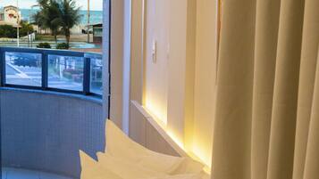 Quarto de hotel com cama, almofadas, janela com vista para a rua e cortinas.