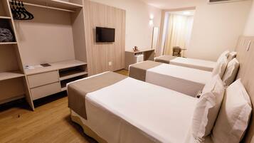 A hotel room with two beds, a TV, a desk, and a wardrobe.