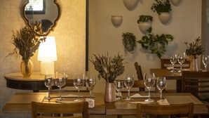 A dining table set with wine glasses and a vase of dried plants, with a mirror and potted plants on the wall. - Hotel da Costa by Nobile (Aracaju)