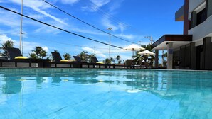 A clear blue pool with lounge chairs and umbrellas, surrounded by palm trees and a modern building. - Hotel da Costa by Nobile (Aracaju)