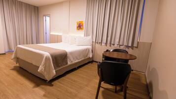 Una habitación de hotel con una cama, un escritorio y una silla.
