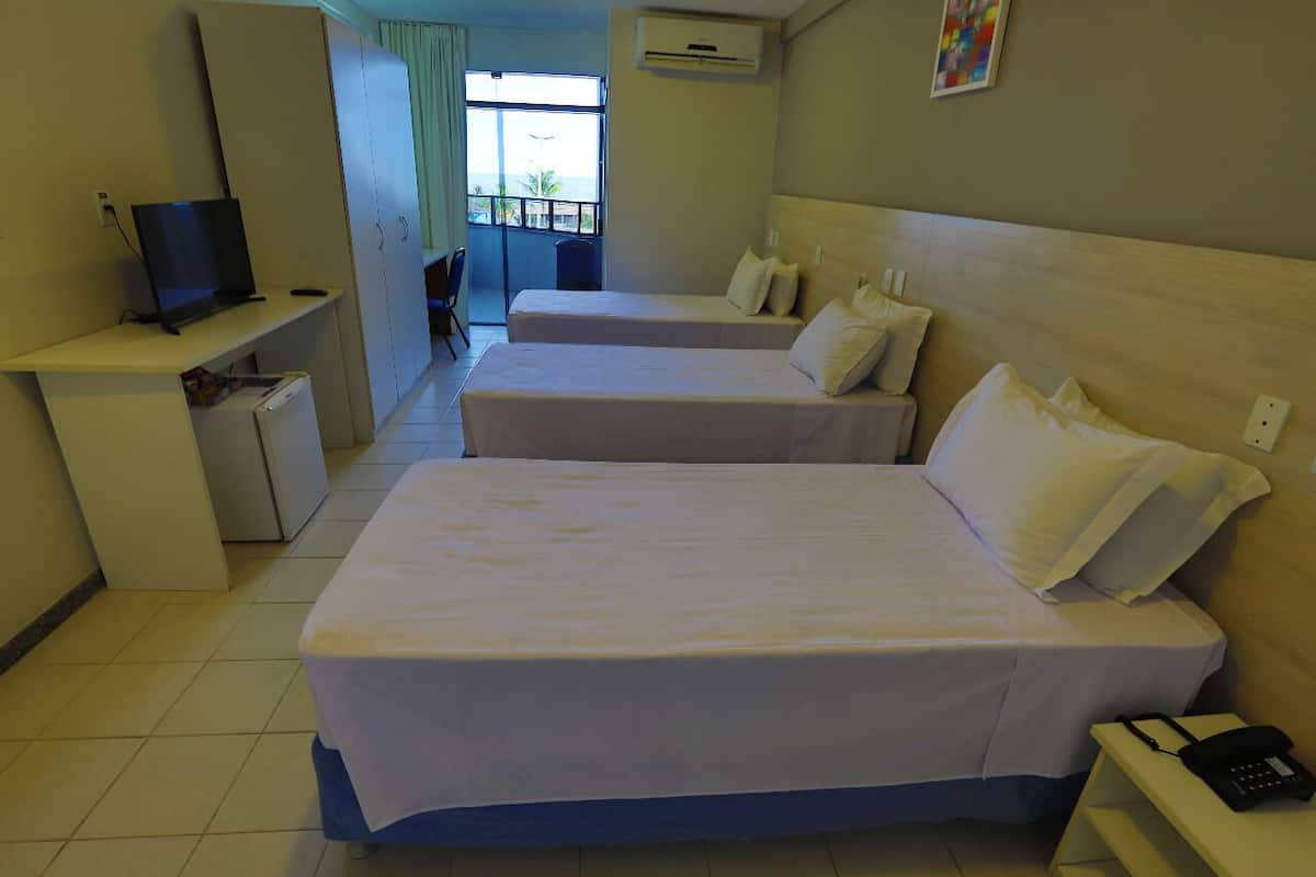 A hotel room with two beds, a desk with a computer, a phone, and a small refrigerator.