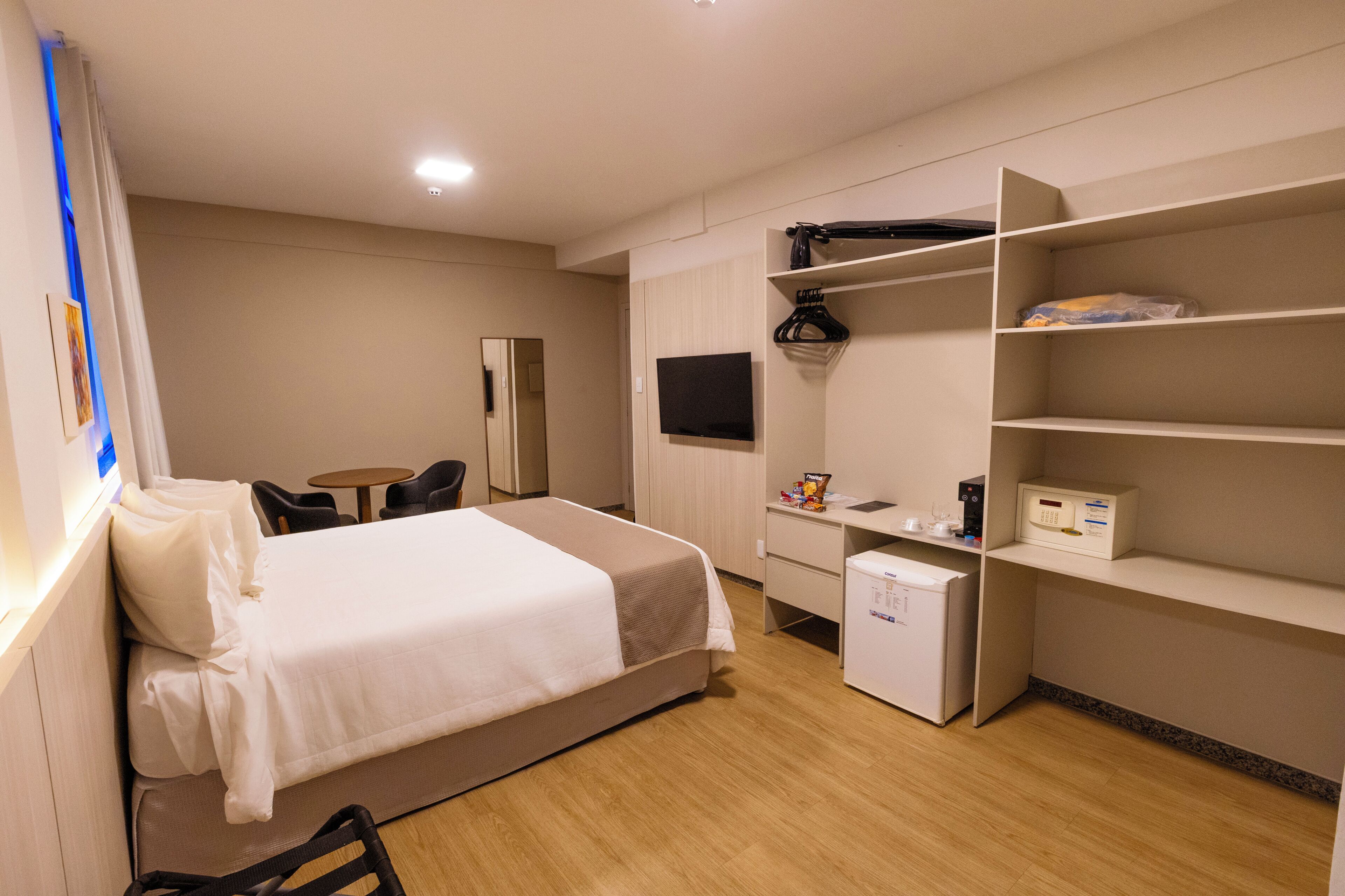 A hotel room with a bed, a desk, a chair, a television, and a wardrobe.