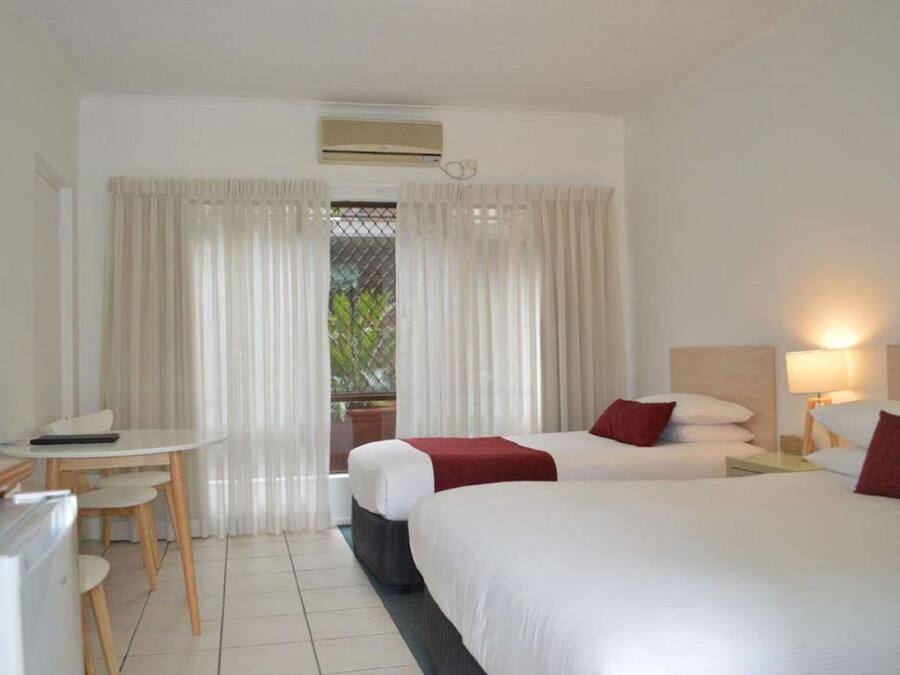Quarto de hotel com duas camas, uma escrivaninha e uma cadeira.