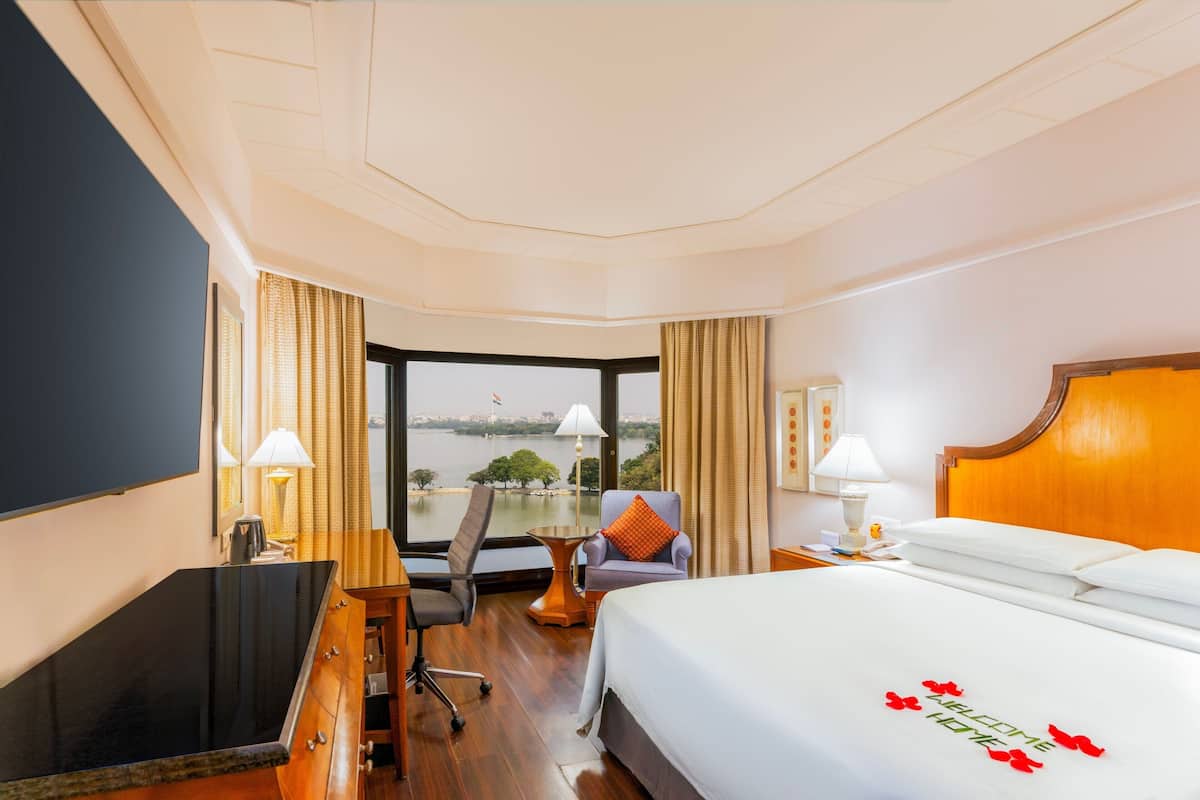 Een hotelkamer met een bed, bureau, stoel en uitzicht op een waterpartij.