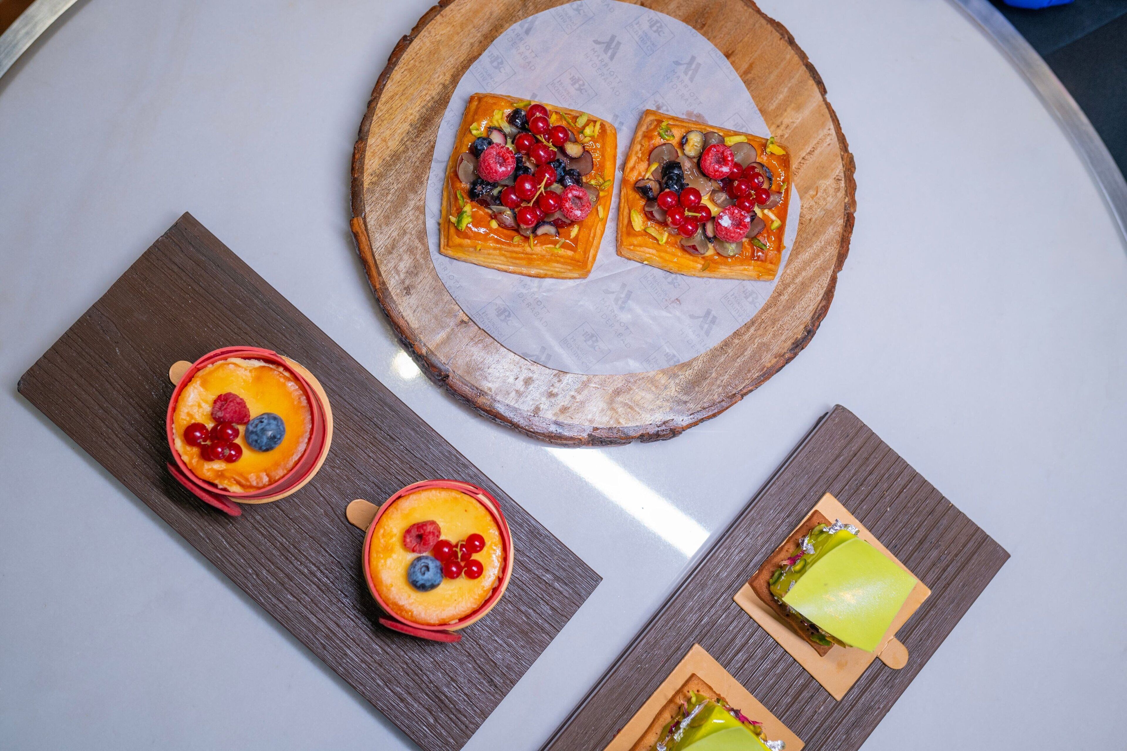 Een rijk gevulde schaal met verschillende patisserieën, gegarneerd met fruit, op een houten plank.