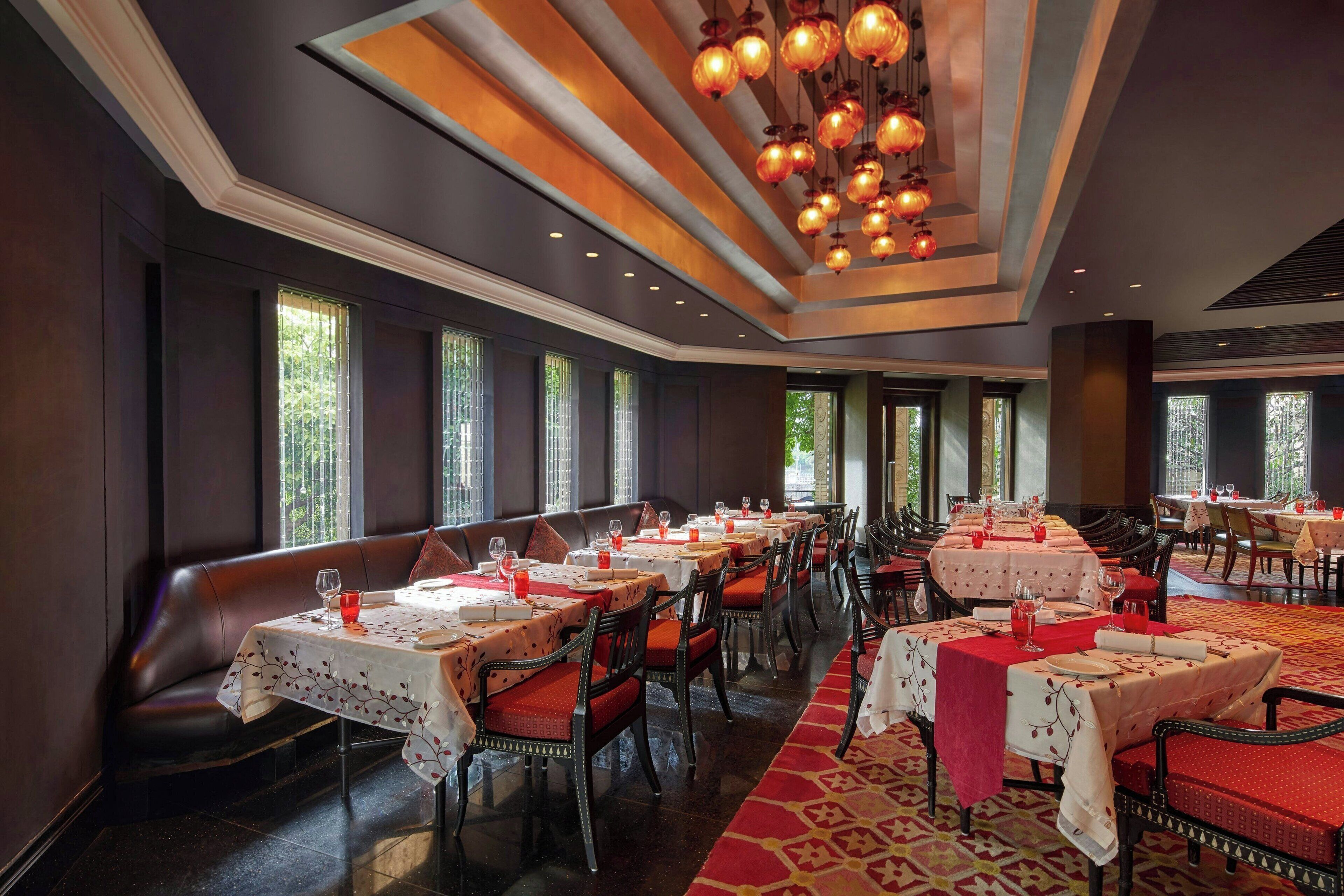 Un restaurant avec plusieurs tables, des chaises et un tapis rouge.